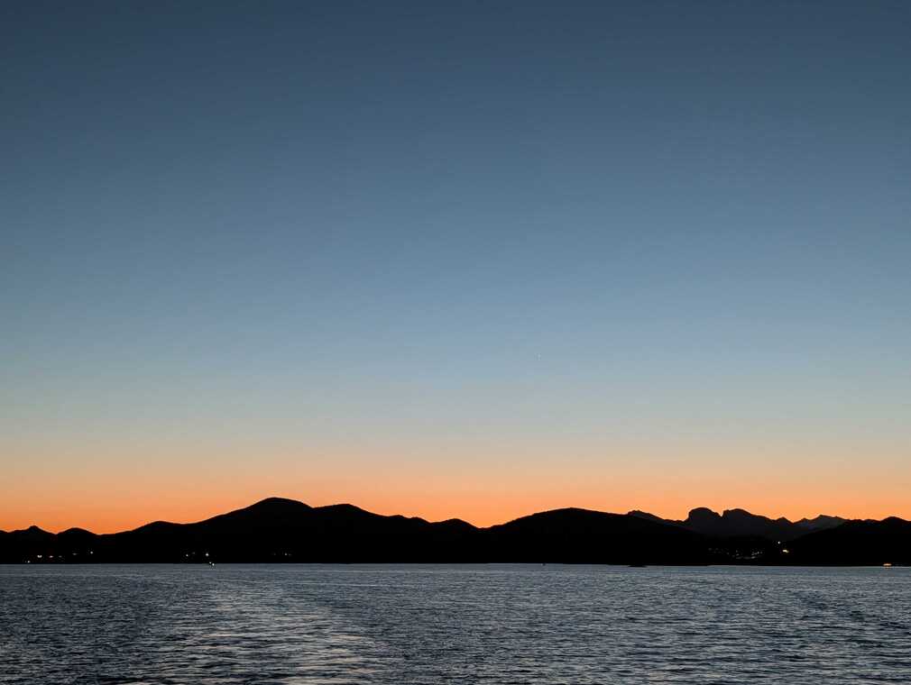 Sunset Over Calm Water with Silhouetted Mountains